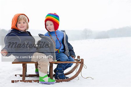 Two boys on a sledge in the snow