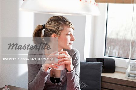 Woman in kitchen, looking out the window