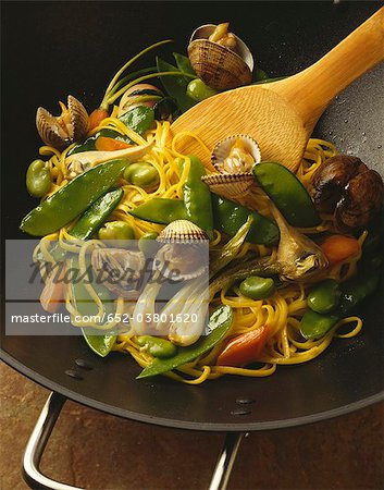 Coquillages cockle chien avec les légumes et les nouilles cuites dans un wok