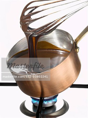 Whipping melted dark chocolate in a copper saucepan
