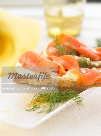Saumon fumé, fromage à la crème et du miel sur une tranche de bouchées de pain Saumon fumé, fromage à la crème et du miel sur une tranche de bouchées de pain