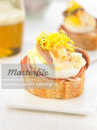 Jambon Serrano, anchois, crevettes et oeufs sur une tranche de bouchées de pain