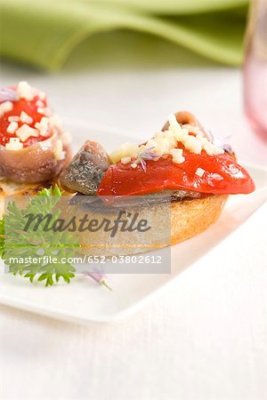 Anchois, poivron rouge et l'ail sur une tranche de bouchées de pain Anchois, poivron rouge et l'ail sur une tranche de bouchées de pain