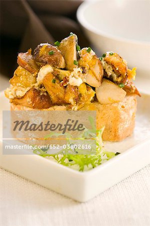 Scrambled eggs and mushrooms on a bite-size slice of bread