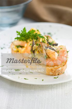 Oeufs brouillés et les crevettes sur une tranche de bouchées de pain Oeufs brouillés et les crevettes sur une tranche de bouchées de pain