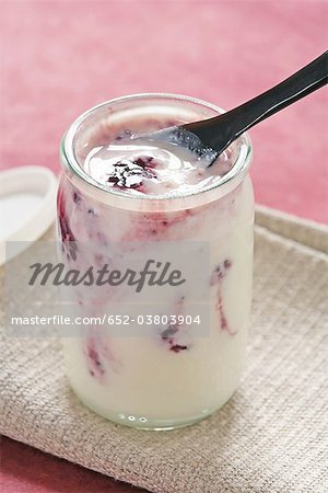 Yogourt nature dans un pot de verre avec de la confiture de blackberry