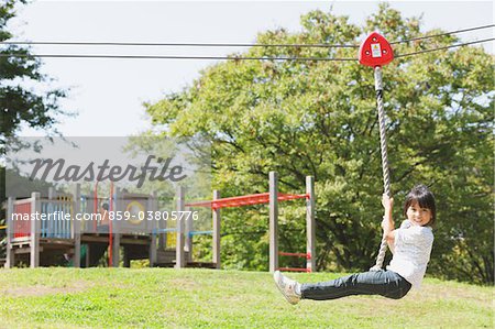 Girl swinging on a rope in playground