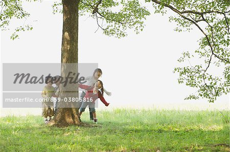 Children Hiding Behind Tree Trunk