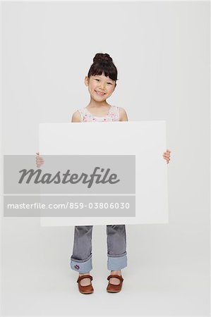 Jeune fille souriante tenant le tableau blanc