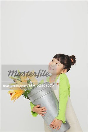 Jeune fille tenant un seau avec des fleurs