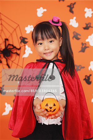 Girl Dressed In Halloween Costume Holding Pumpkin Bucket