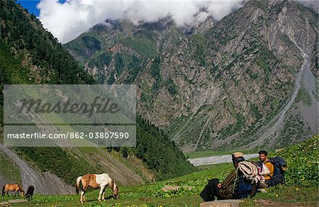 India, Himachal Pradesh, Chamba Valley. Gaddi (semi-nomadic shepherds) villagers from Kugti village pause near meadows known as Duggi Got on the trail linking Kugti village, Kugti Pass and the summer grazing meadows of Lahaul.