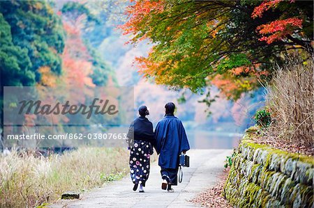 Asia, Japan. Kyoto, Sagano, Arashiyama, couple walking next to river, autumn leaves