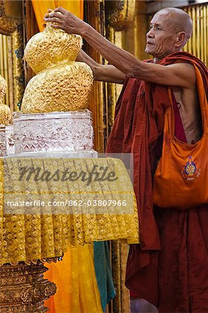 Myanmar, en Birmanie, le lac Inle. Un moine s'applique la feuille d'or à l'un des cinq Bouddhas, maintenant transformés en un blob par le foisonnement de feuille d'or appliquée au cours des années, Phaung Daw Oo Paya.