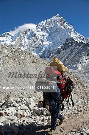 La vallée de Khumbu au Népal, région de l'Everest. Sur les hauteurs de l'Everest Base Camp trail un lourdement chargé et Las porter fait son chemin dans le paysage glaciaire stérile.