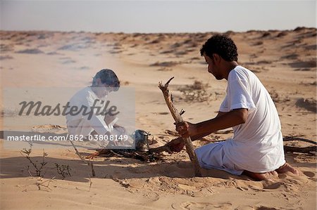 Oman, Wahiba Sands. Un guide bédouin et son fils faire un feu pour faire un café. Oman, Wahiba Sands. Un guide bédouin et son fils faire un feu pour faire un café.