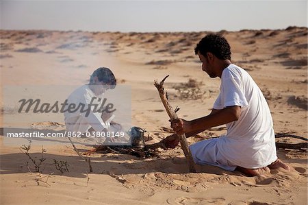 Oman, Wahiba Sands. A Bedouin guide and his son make a fire to make a coffee.