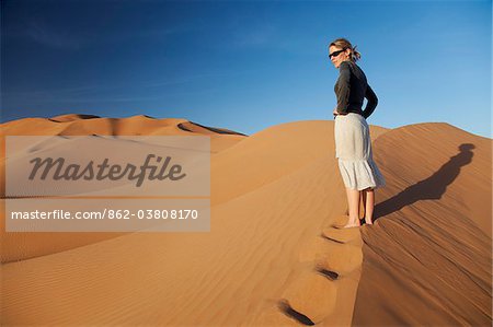 Oman, Empty Quarter. Oman, Empty Quarter. Une jeune femme debout au sommet d'une dune.