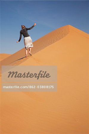 Oman, Empty Quarter. A young lady makes her way up the steep dunes.