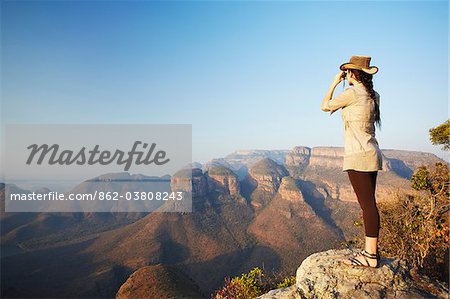 Woman looking through binoculars at Three Rondavels, Blyde River Canyon, Drakensberg Escarpment, Mpumalanga, South Africa