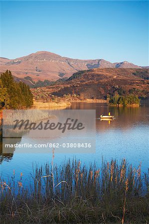 Fishing boat on lake with Drakensberg mountains in background, Ukhahlamba-Drakensberg Park, KwaZulu-Natal, South Africa