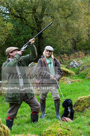 North Wales, Snowdonia ; Gilar Farm. A man and woman out shooting with their spaniel retriever.