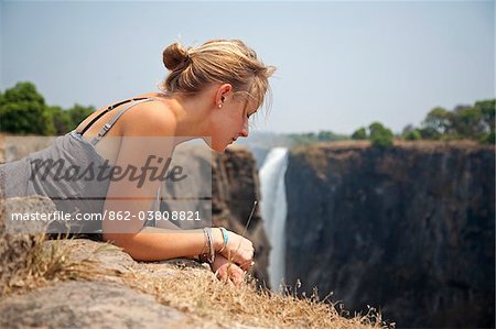 Zimbabwe, Victoria Falls. Une jeune fille regarde par-dessus le bord des chutes Victoria.