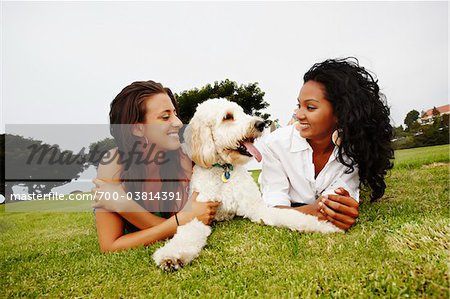 Zwei Frauen, die auf Gras mit Hund liegend
