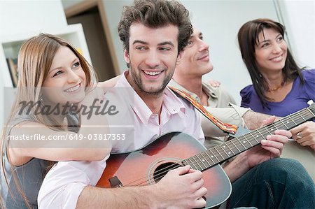 Happy friends playing guitar together