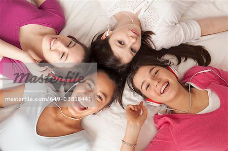 teenage girls lying on floor listening to music, smiling