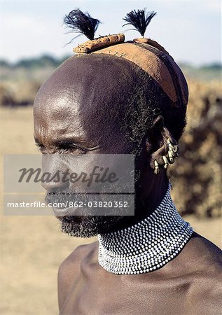 A Dassanech elder wearing a traditional clay hairdo, topped with ostrich feathers. His broad beaded necklace is unusual for its size but his five brass earrings are a common decoration of both men and women.The Dassanech people live in the Omo Delta of southwest Ethiopia, one of the largest inland deltas in the world.