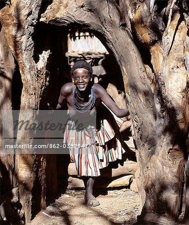 A young woman at the entrance to a Konso homestead in southwest Ethiopia.The konso have a great affinity for wood and stone, large tree trunks and branches surround every home, and special care is taken to select the most pleasing shapes for their entrances.