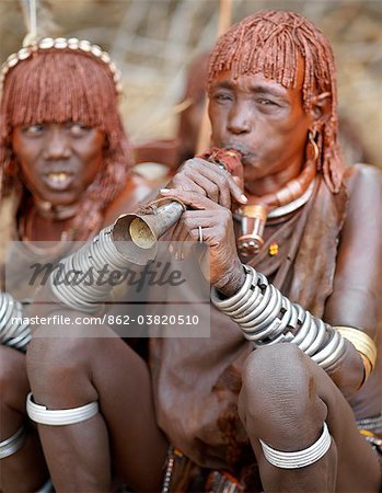 Une femme de Hamar souffle une trompette étain à un saut de la cérémonie du taureau.Le Hamar sont des bergers nomades du sud-ouest de l'Éthiopie dont les femmes portent suppression de style et costumes traditionnels leur mode de mop rouge cheveux ocrées semi.Le saut de la cérémonie de Bull est un rite de passage pour les jeunes hommes.