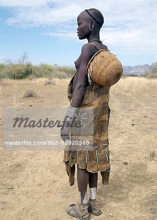 Eine Mursi-Mädchen, gekleidet in fein dekoriert Lederbekleidung mit einem schön gemacht Korb über einer Schulter. Teilweise rasierten Kopf ist die typische Frisur von ihres Stammes.Die Mursi sprechen eine nilotische Sprache und Affinitäten mit den Schilluk und Anuak östlichen Sudan haben. Sie leben in einem abgelegenen Gebiet im Südwesten Äthiopiens Omo Fluss, größte Fluss des Landes.