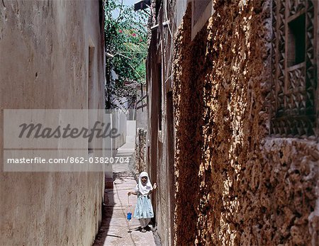 A young schoolgirl walks home along one of the narrow streets of Lamu town.Situated 150 miles north northeast of Mombasa, Lamu town dates from the 15th century AD. The islands importance lies in the fact that it has the only certain source of sweet groundwater in the entire district.