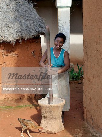 Une femme malgache moud le maïs à l'aide d'un mortier et un pilon en bois dans un joli village malgache du peuple Betsileo, qui vivent au sud-ouest de la capitale, Antananarivo.Most maisons construites par les Betsileo sont doubles étages avec une cuisine et d'habitation situé au premier étage.Bétail est souvent conservé au rez de chaussée d'une maison pendant la nuit.