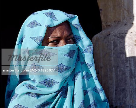 Une femme Nubienne, son visage couvert par son foulard pour désigner sa croyance musulmane, se trouve à l'extérieur de la véranda de sa maison.Le style de l'arc de la véranda est typique du peuple nubien.