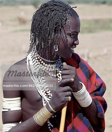 Datoga jeune homme en habit traditionnel.Ses tresses sont ornés de perles et ouvre-boîtes en aluminium.Bon nombre de ses bracelets en plastique blancs sont joliment décorées avec des conceptions abstraites et géométriques ; Il y a longtemps ces bracelets auraient été faits d'Ivoire.