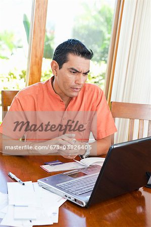 man at table with bills and laptop