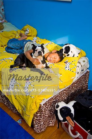 Junge mit Hund auf dem Bett schlummern
