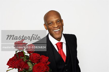 Un homme vêtu d'un costume et tenant un buncht de roses rouges