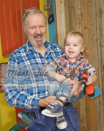 A senior man doing carpentry with his grandchild, Sweden.