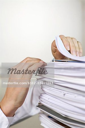 Two hands browsing through a pile of paper in an office.