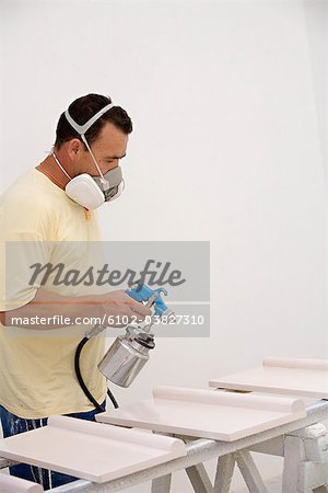 A man wearing a protective mask painting.