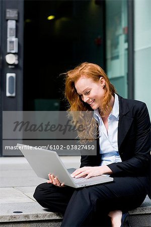 Woman sitting outdoors using her lapptop, Stockholm, Sweden.