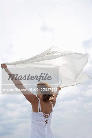 Une femme tenant une écharpe blanche dans le vent de la mer, Suède.