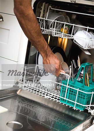A hand taking out dishes from a dishwasher.