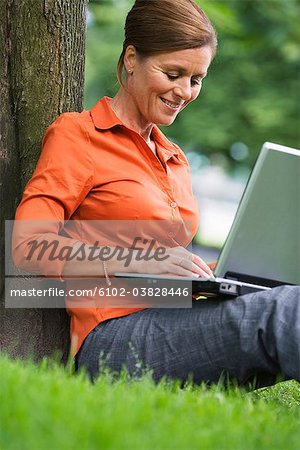 A woman in a park using a laptop, Sweden.