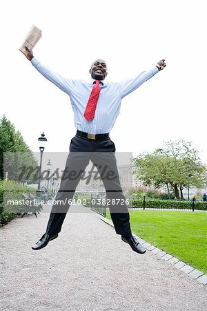 Un homme d'affaires sautant dans un parc, Stockholm, Suède.