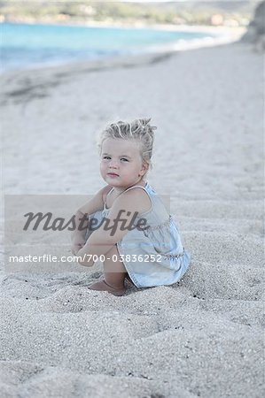 Petite fille assise sur la plage
